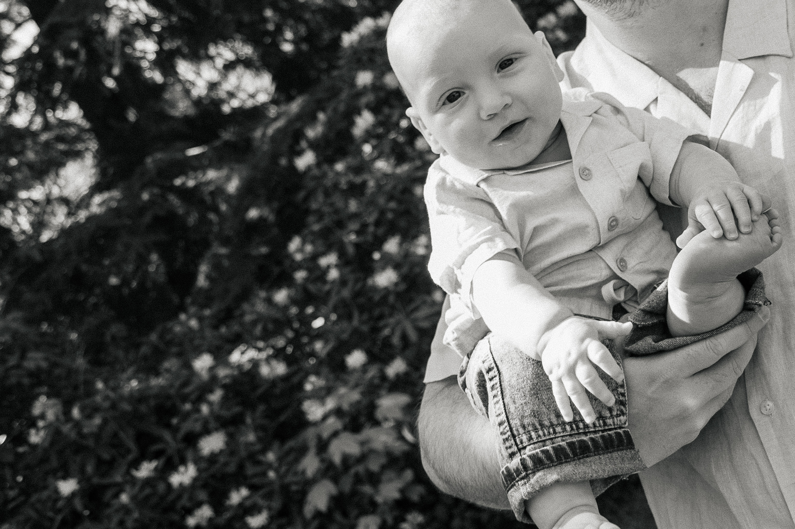 black-and-white dutch angle photo of dad holding is 6-month old son.