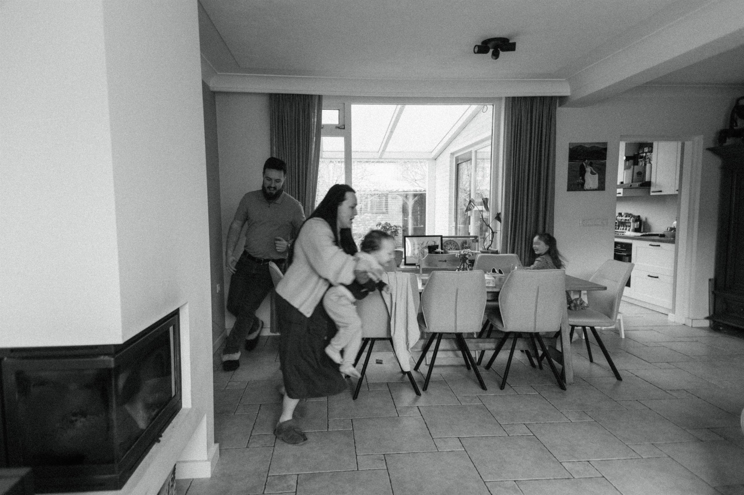 Black-and-white family photo gathered around a dining table at home.