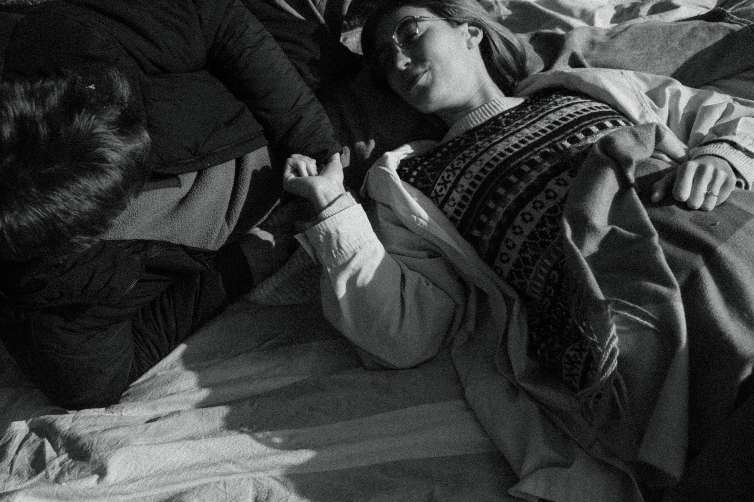 Black-and-white close-up of a couple lying together and holding hands.