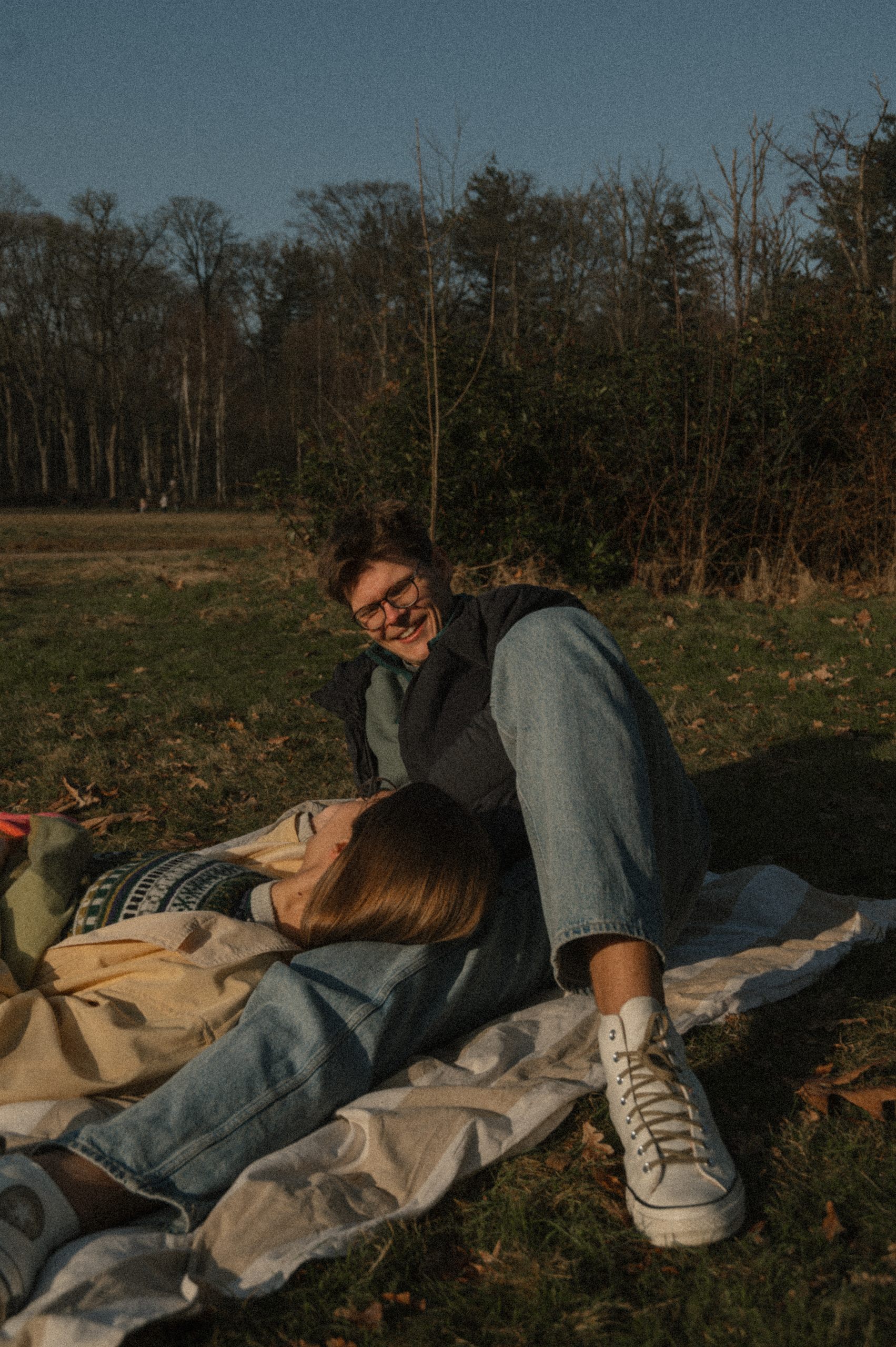 Couple cuddling on a picnic blanket outdoors.