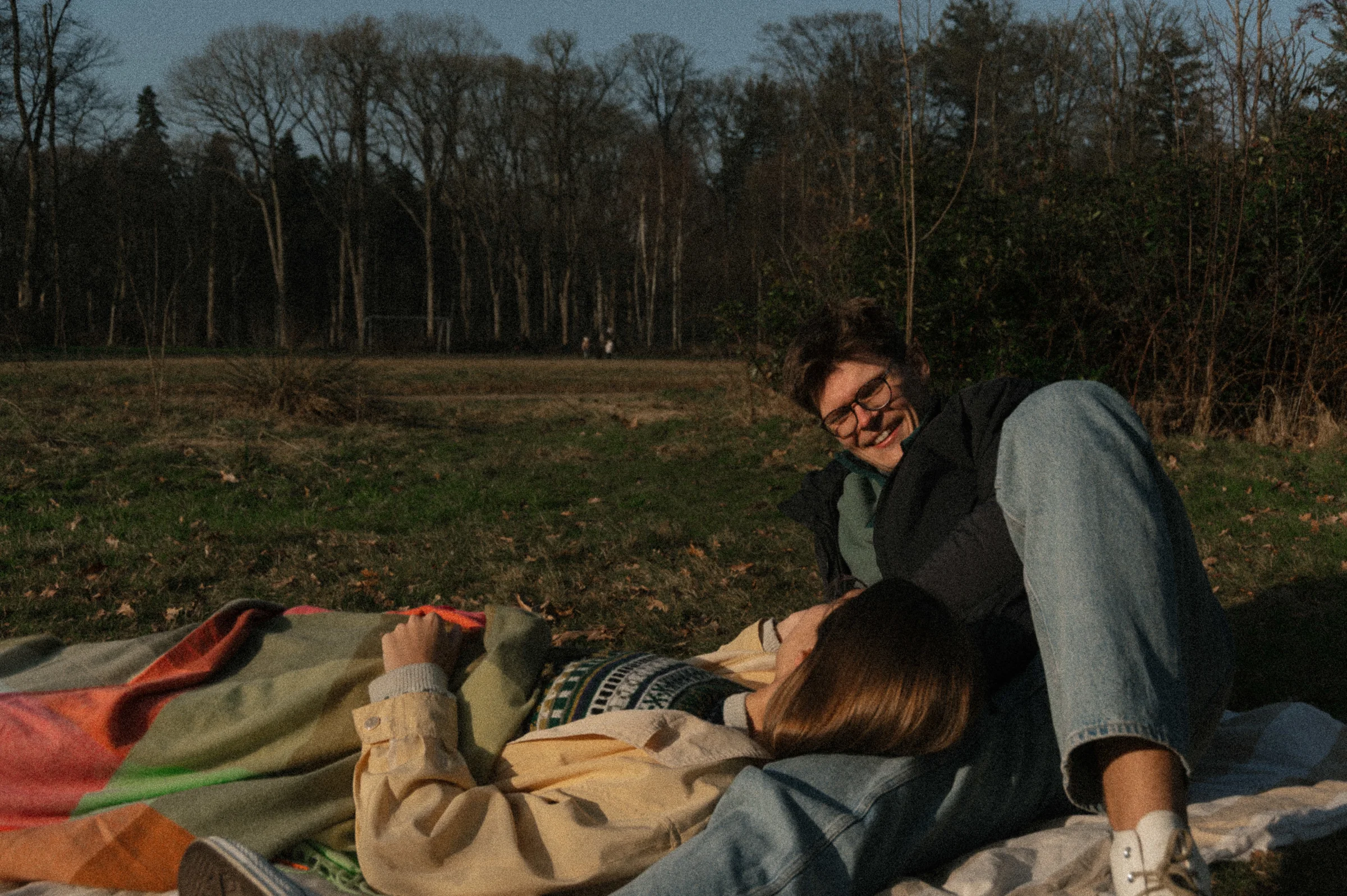 couple lying on picnic blanket in park