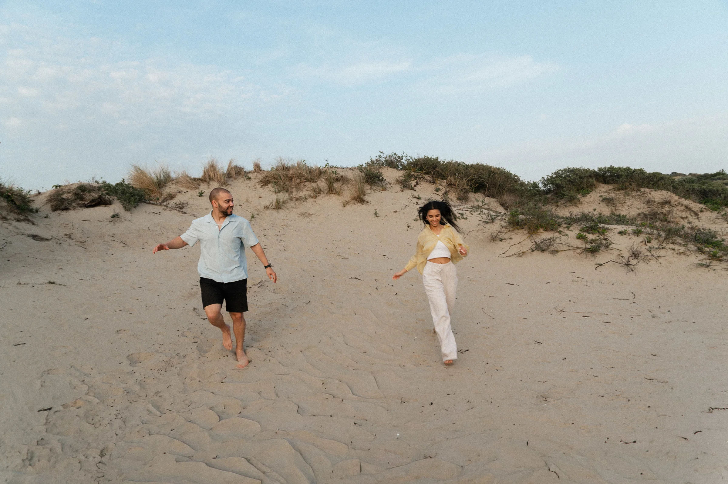 couple running down sand dune on beach