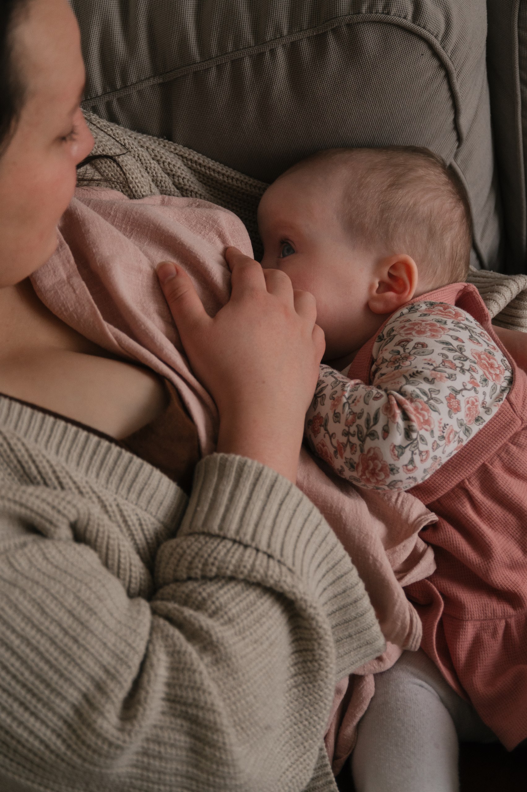 Mother breastfeeding her newborn while resting together on a bed.