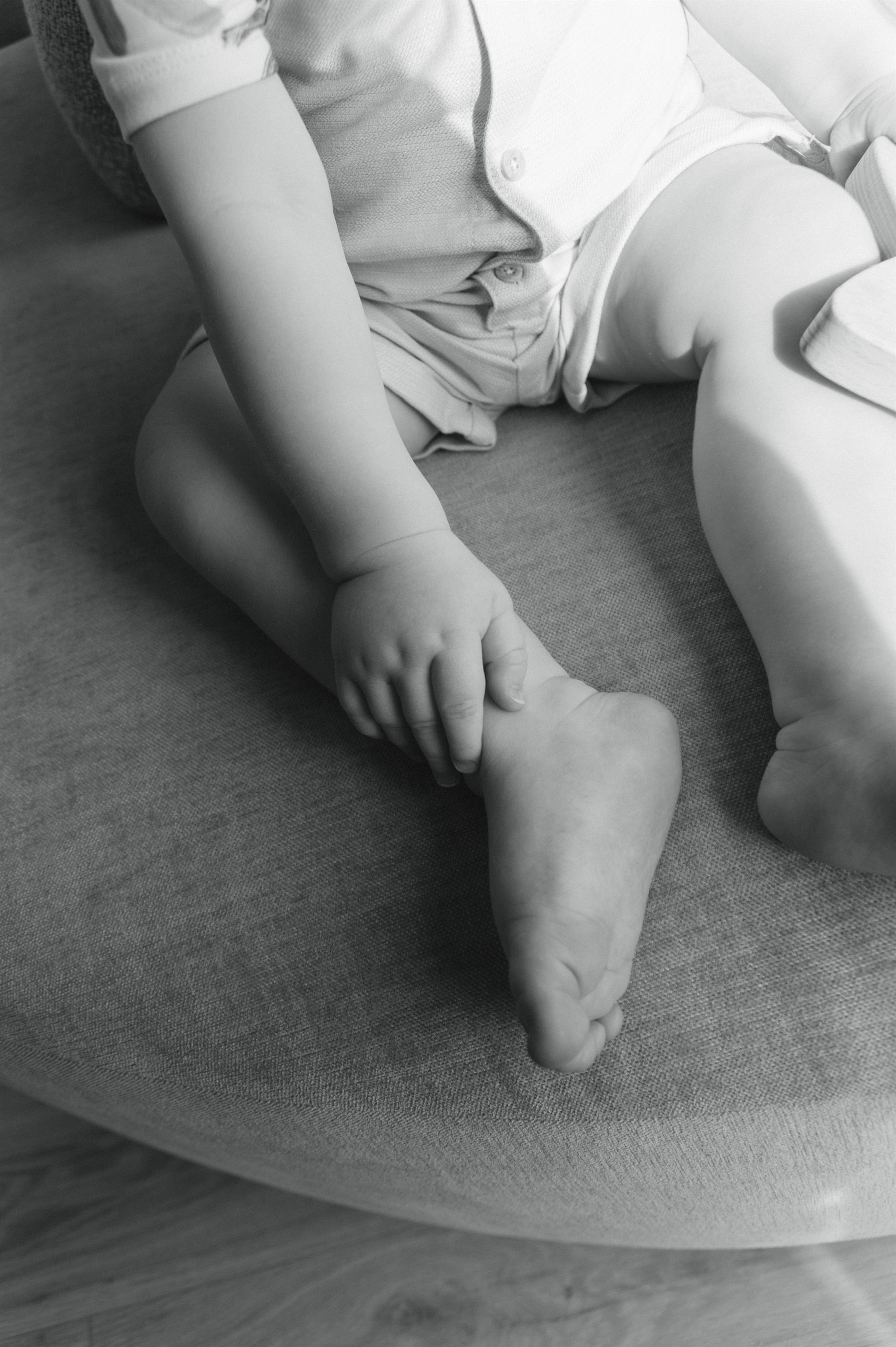 Black-and-white close-up of a toddler beside a newborn on a blanket.