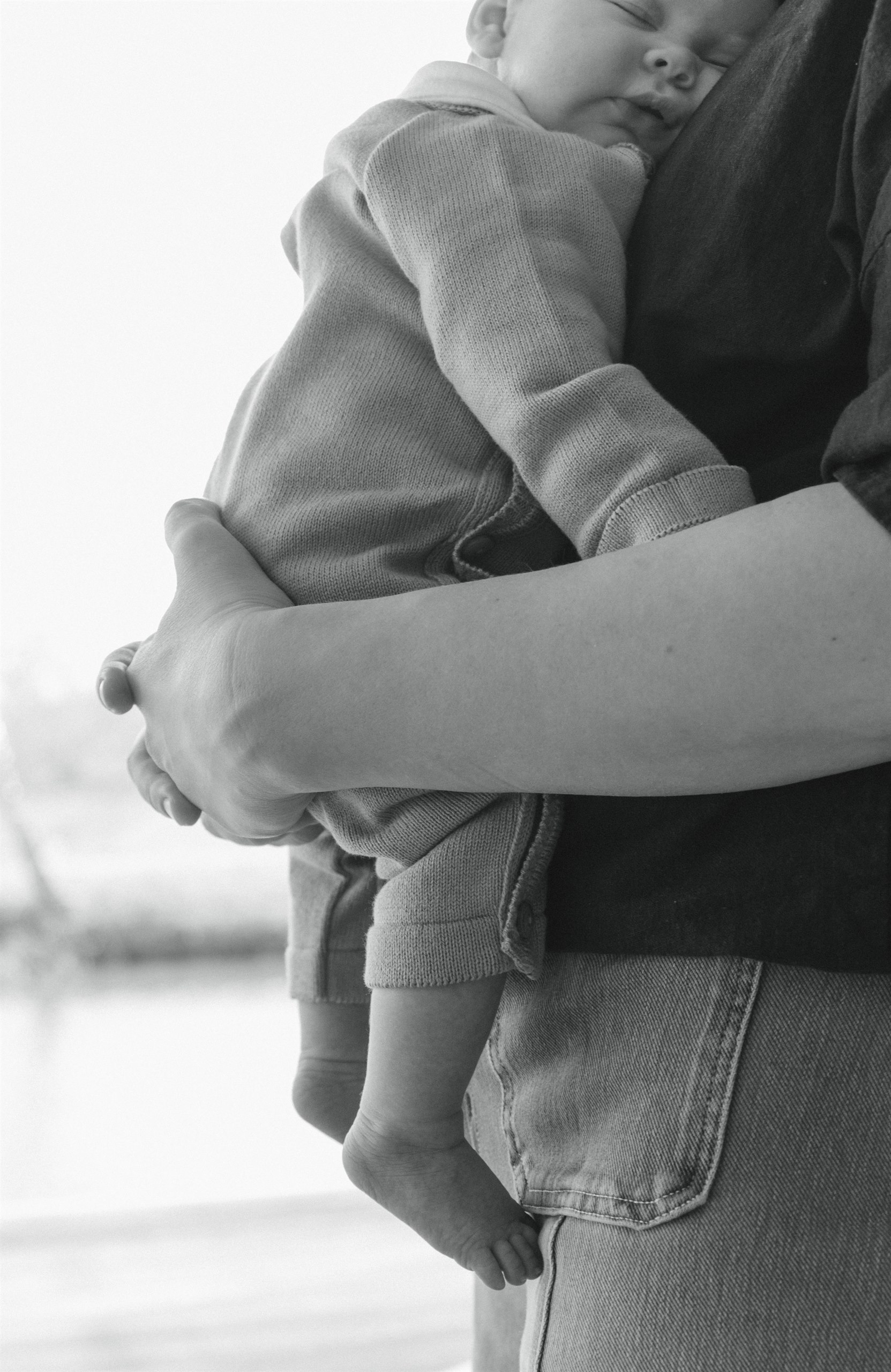Black-and-white close-up of a child being held against a parent's shoulder.
