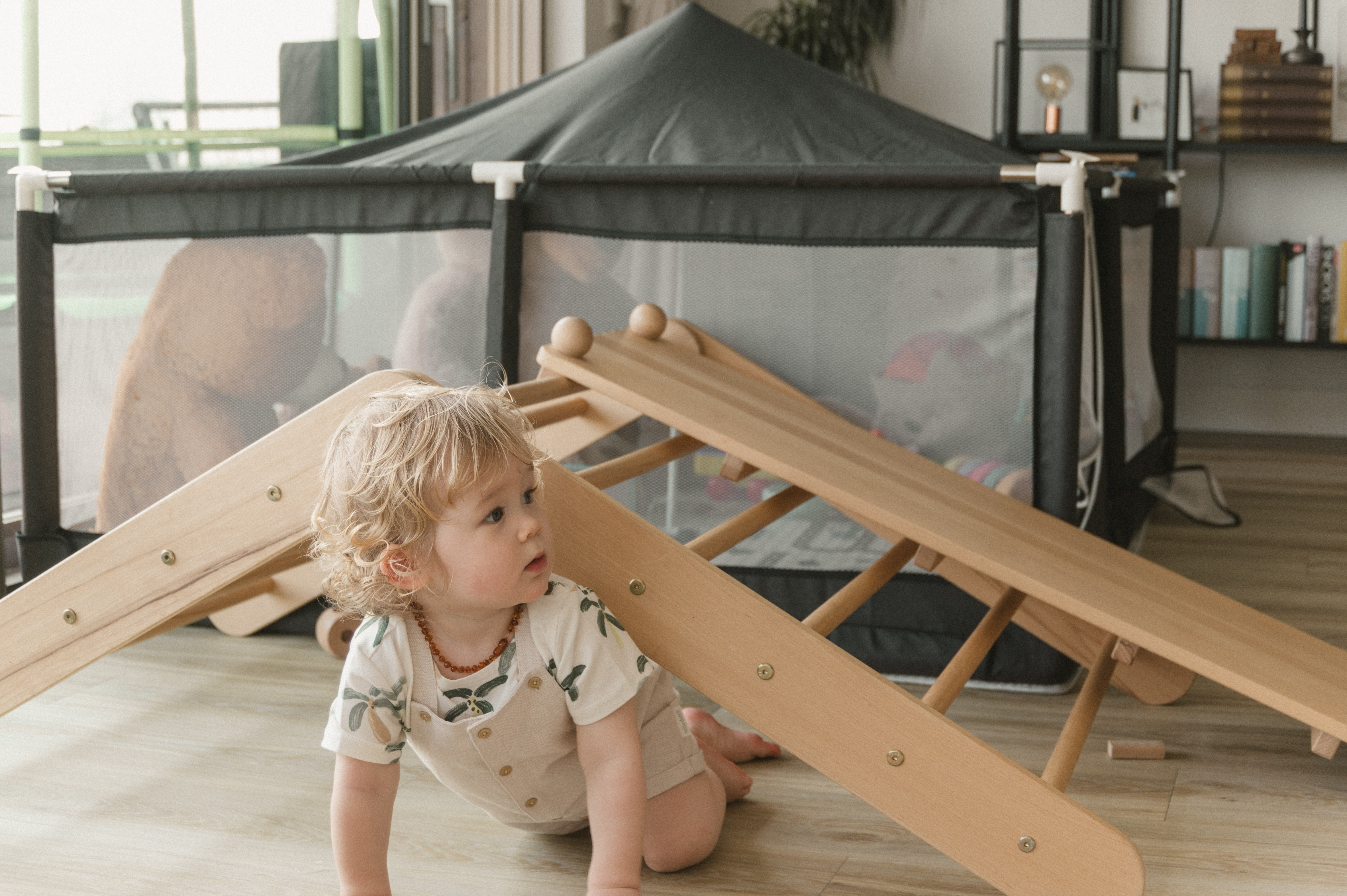 Toddler crawling beneath a small indoor climbing frame.