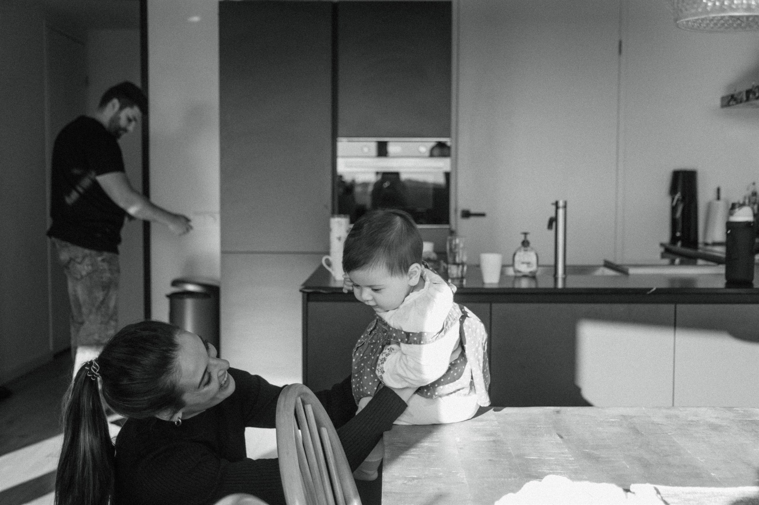 Black-and-white family scene in the kitchen with parents and children together.