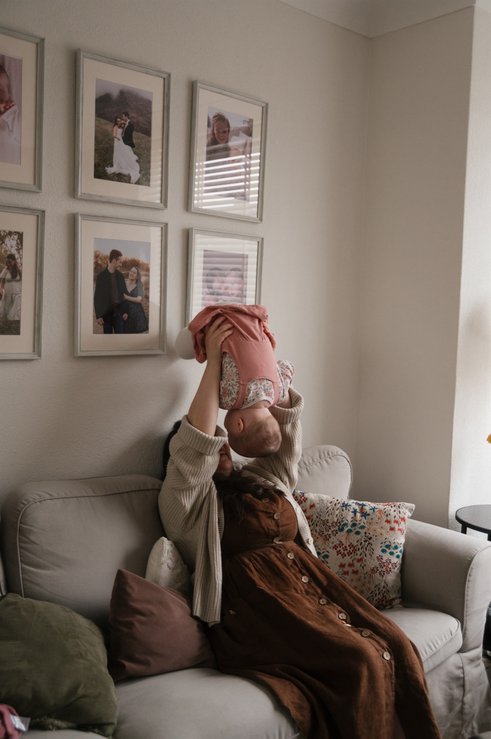 Mother lifting her baby in a bright living room.