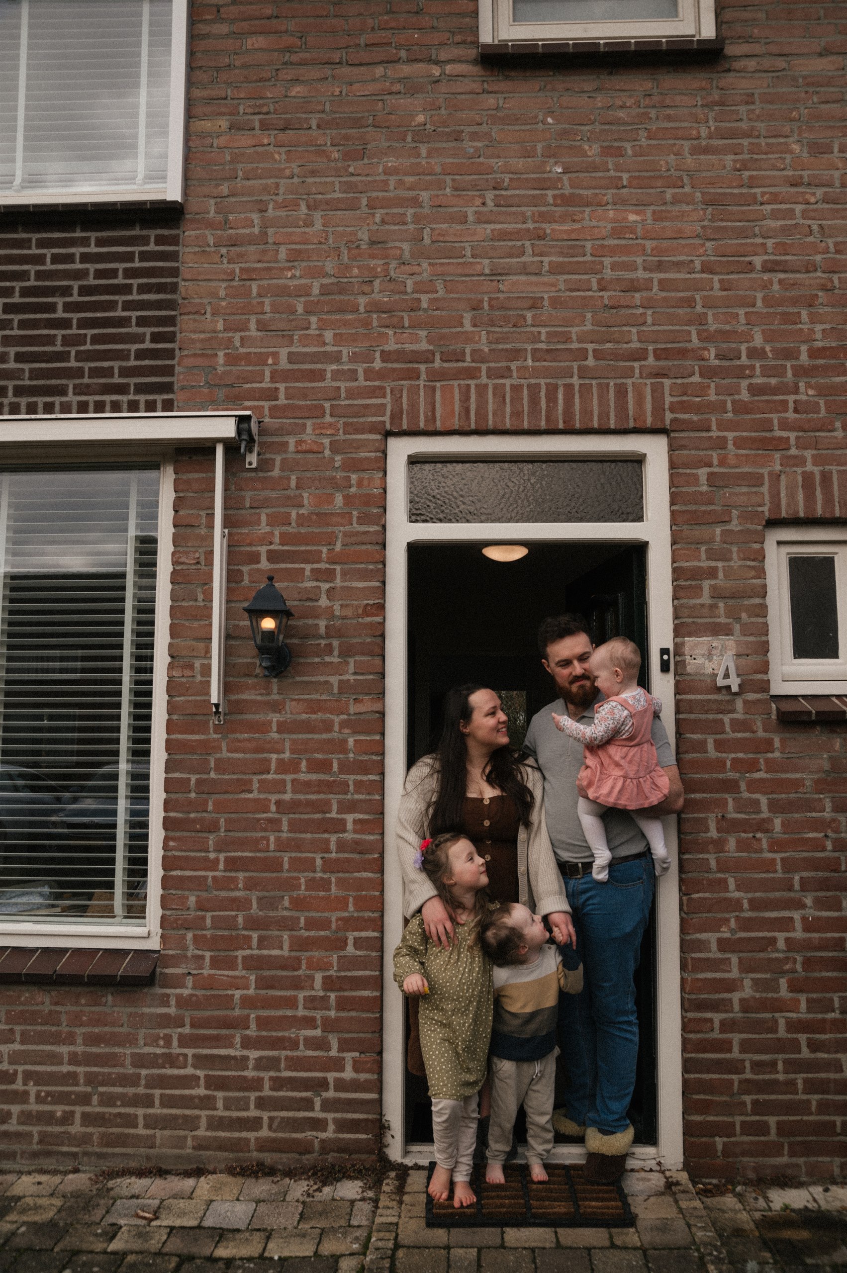 Family gathered together in the doorway of their brick home.