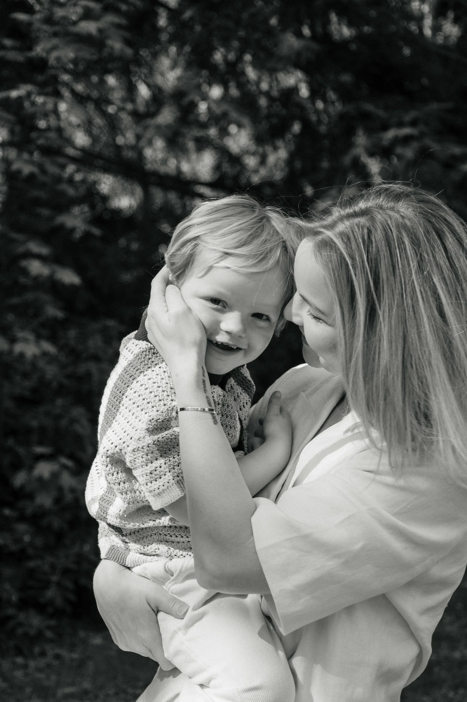 Black-and-white image of mother holding her 4 year old son pressing her hear against his.