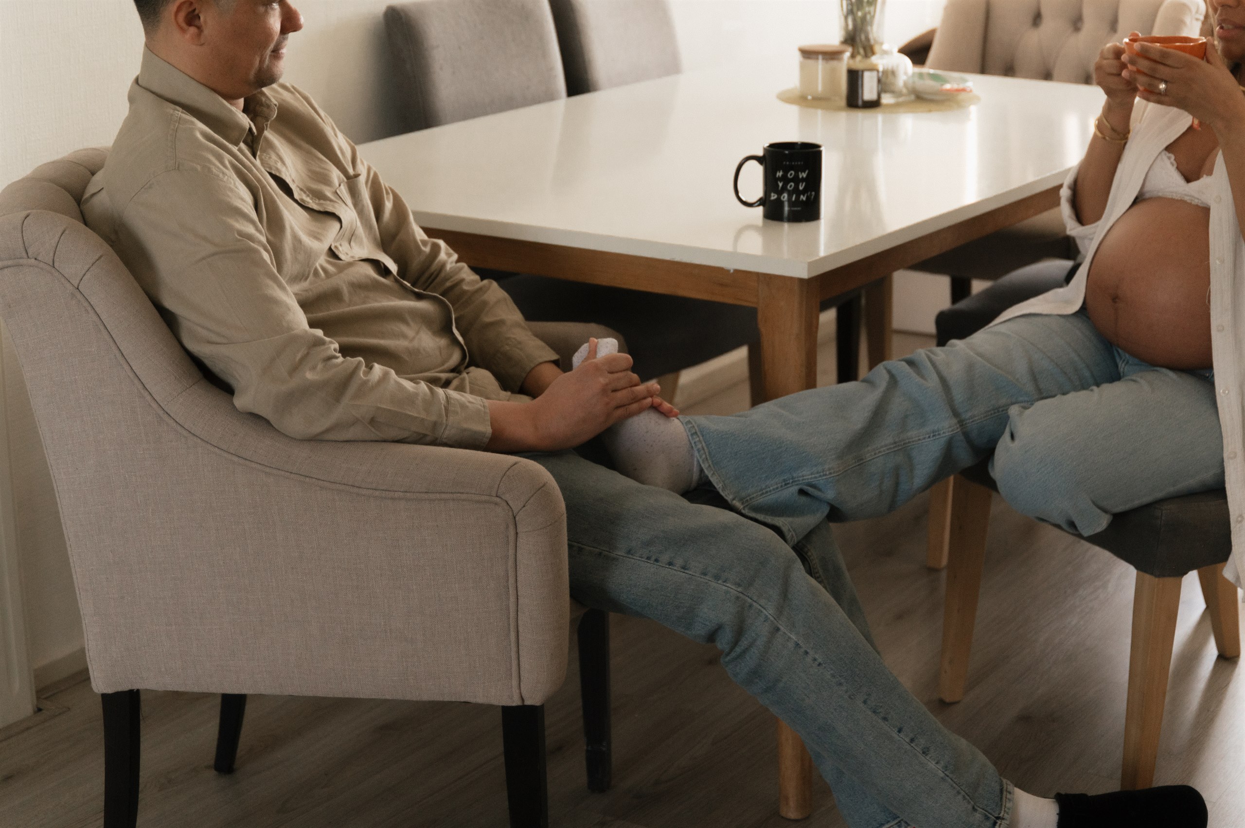 Expectant couple seated together at home with the mother's belly visible in frame.