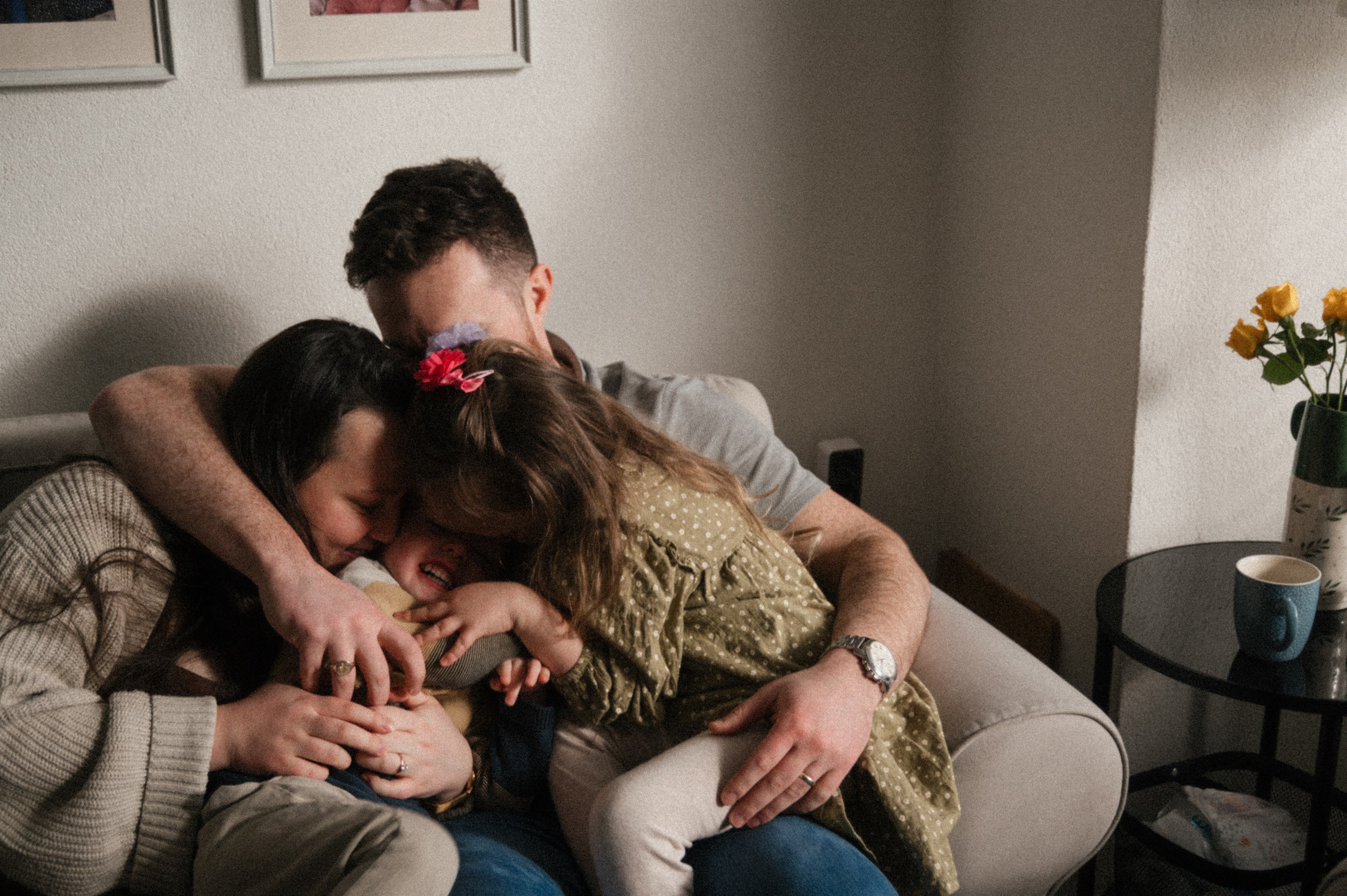 Family cuddling together on a sofa with their children.