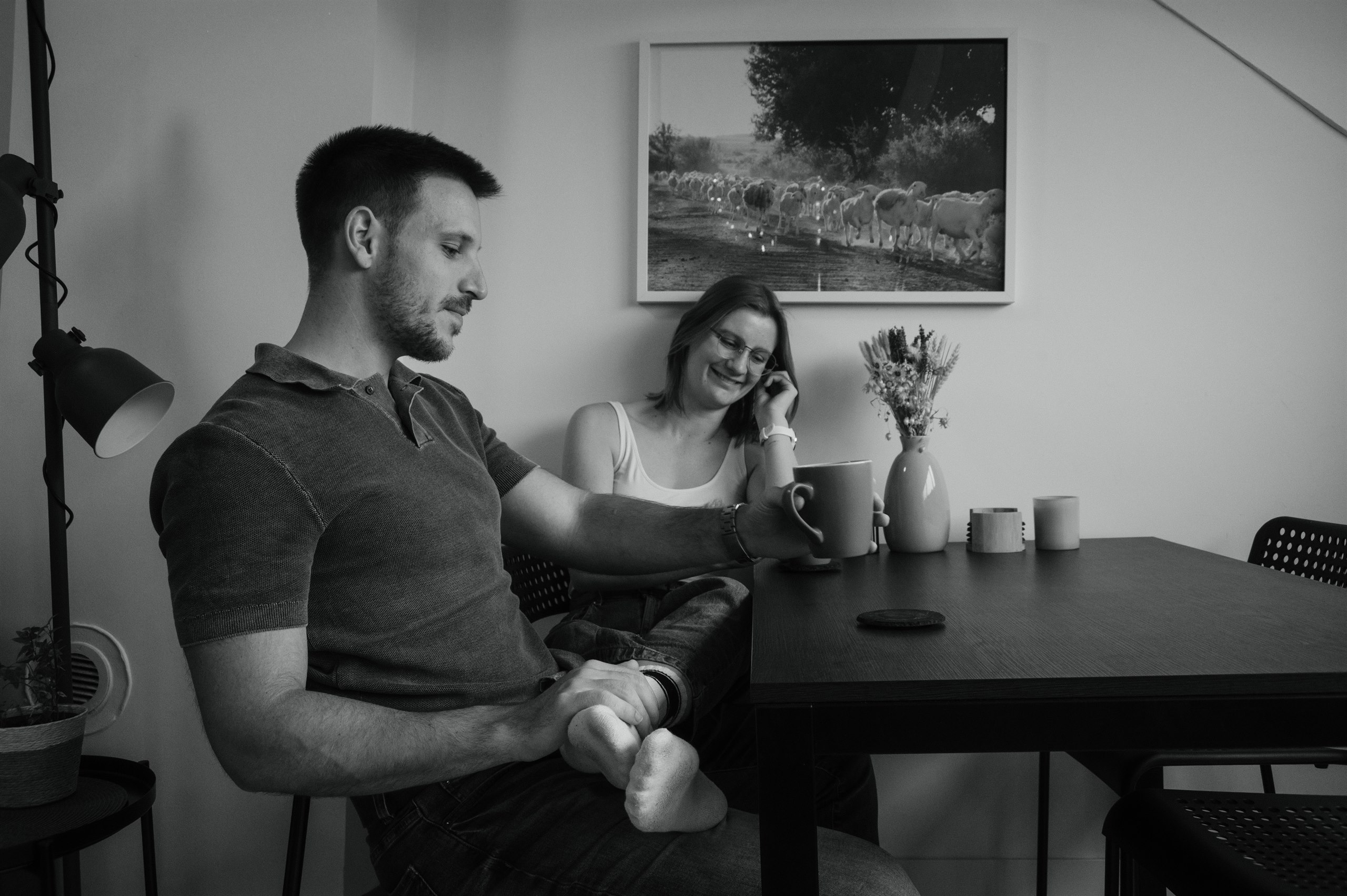 Black-and-white candid of a couple seated together at their dining table.