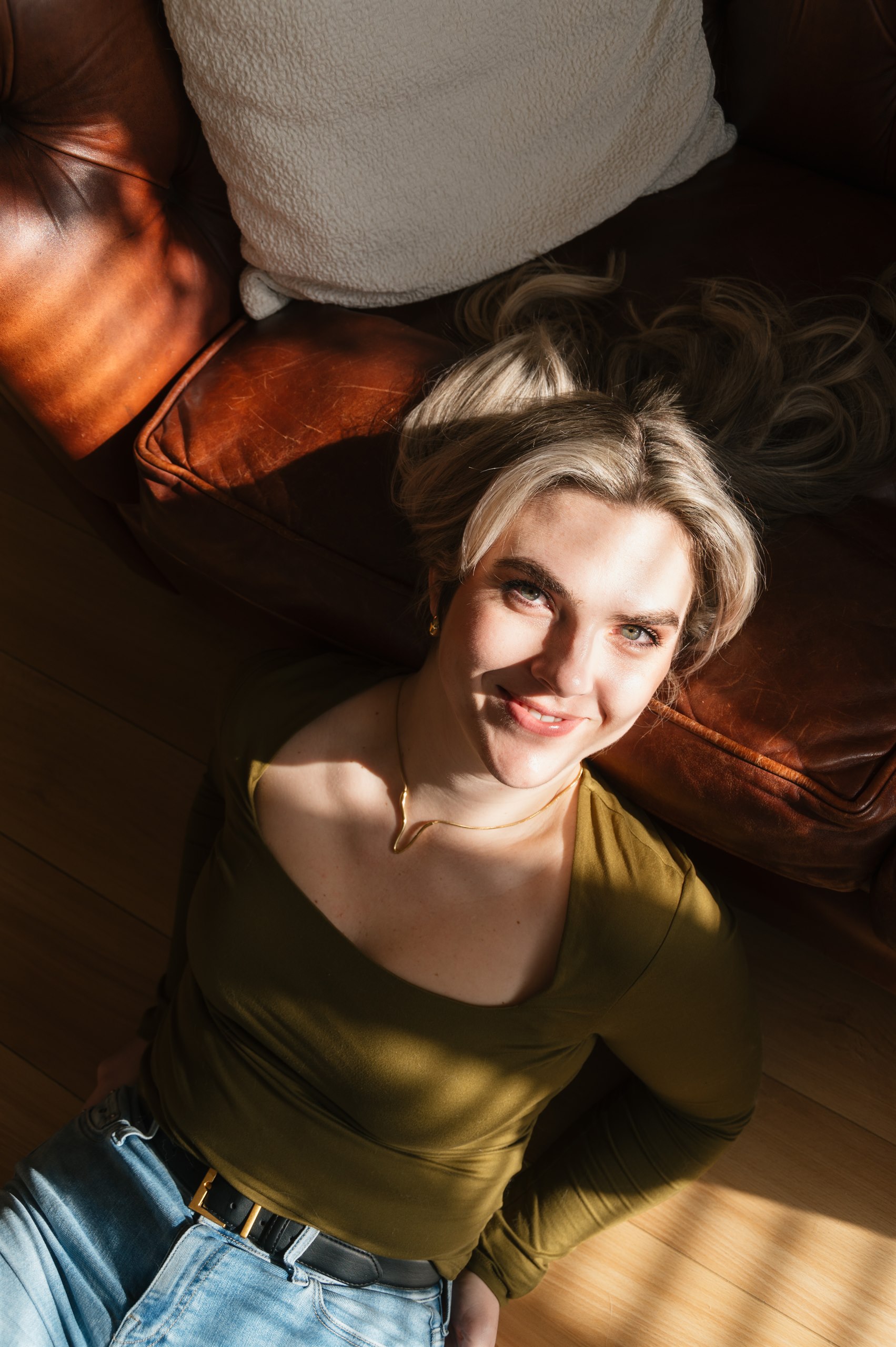 Portrait of a woman lying on the floor in warm striped sunlight.