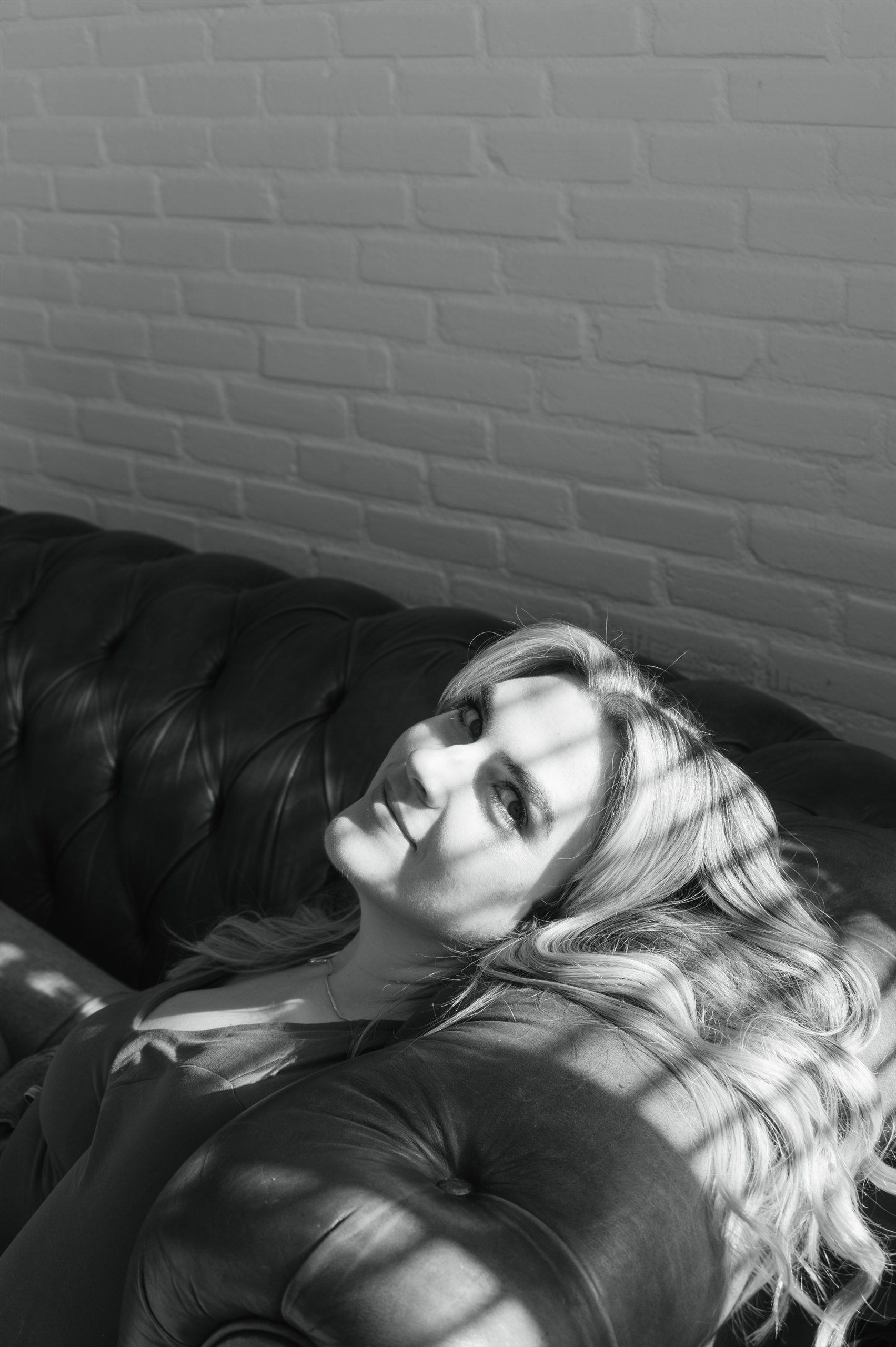Black-and-white portrait of a woman reclining on a sofa.