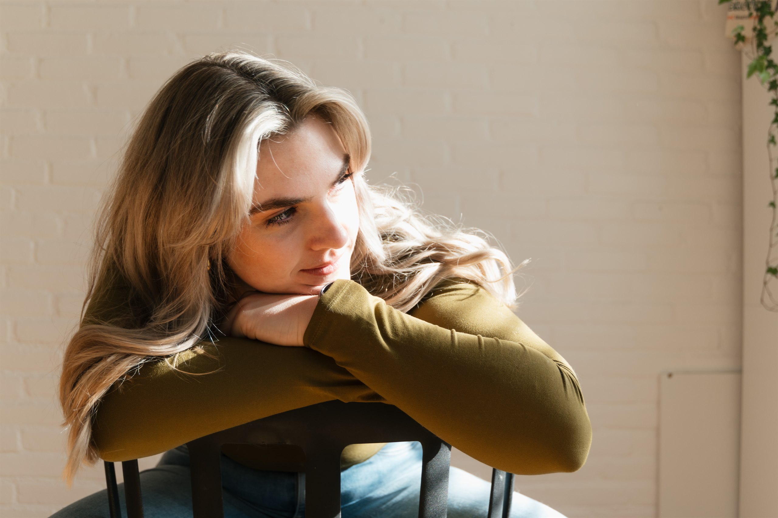 Portrait of a woman resting her arms on a chair in warm sunlight.