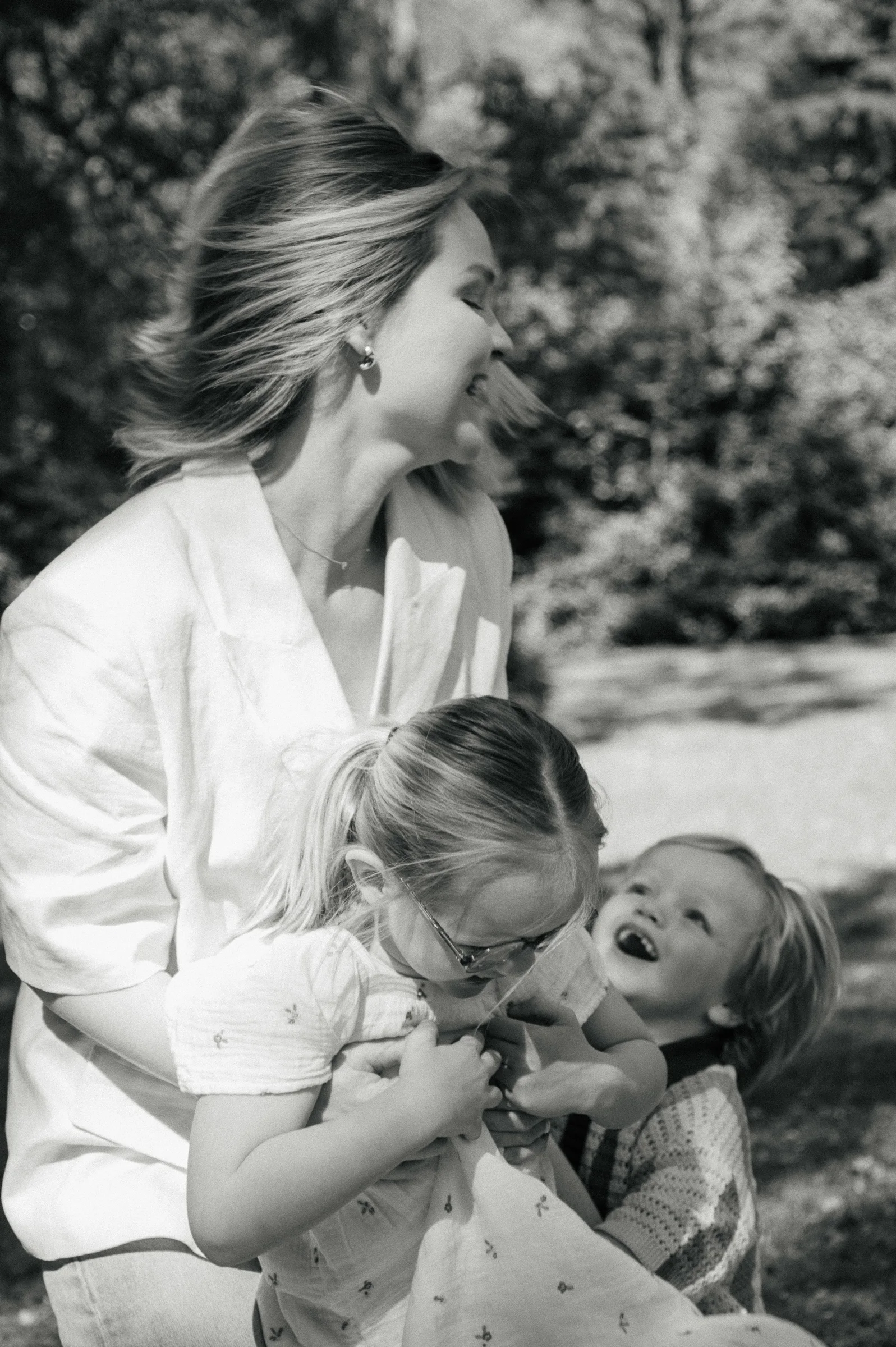 black and white image of mother playing with daughter and son